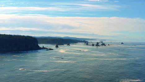 Impresionante-Toma-Aérea-De-Camiones-Con-Drones-De-La-Hermosa-Tercera-Playa-En-Forks,-Washington,-Con-Grandes-Formaciones-Rocosas,-Acantilados,-Pequeñas-Olas-Y-Espuma-Marina-En-Una-Cálida-Y-Soleada-Mañana-De-Verano.