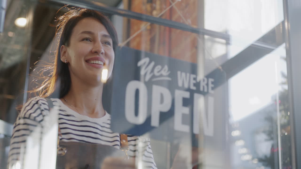 Titolare di attività commerciale che appende il cartello Aperto/Chiuso