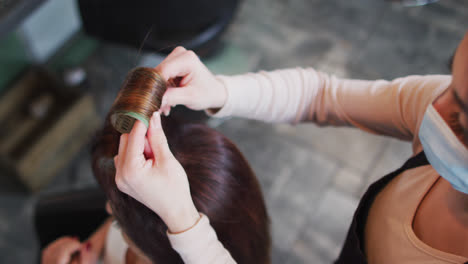 Eine-Friseurin-Mit-Gesichtsmaske-Legt-Lockenwickler-In-Das-Haar-Einer-Kundin-Im-Friseursalon