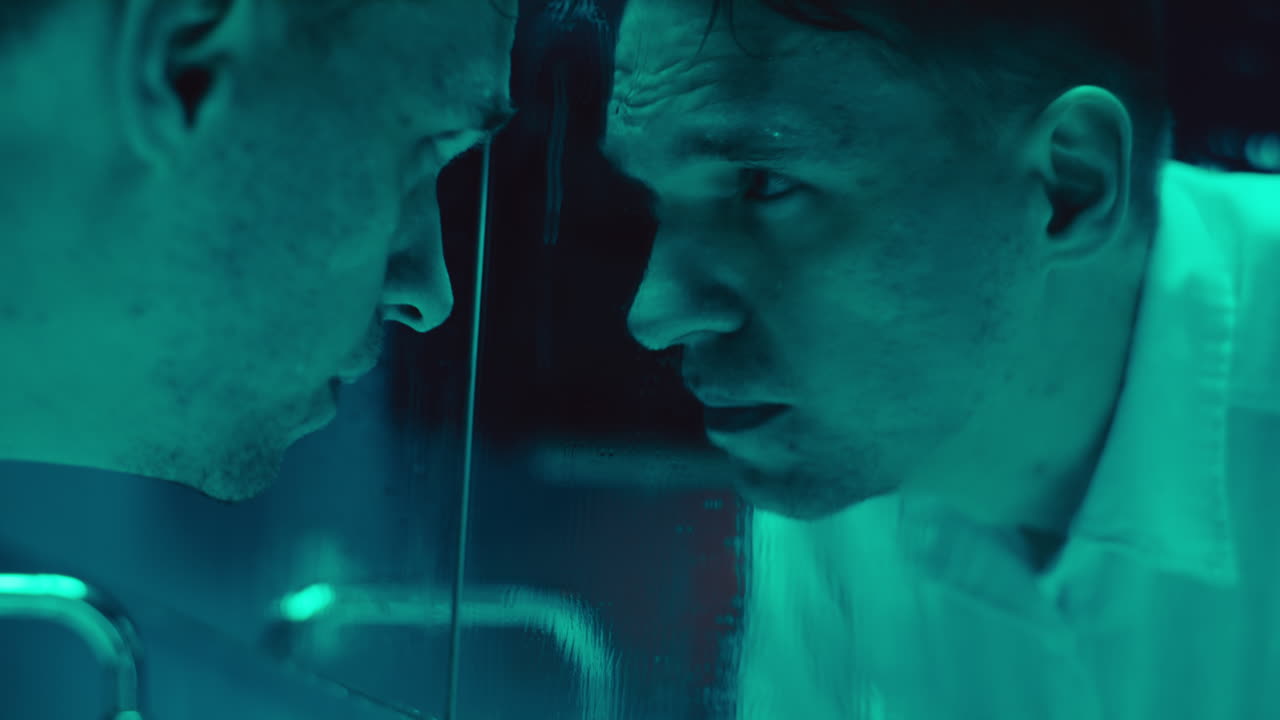 Man staring at his reflection in a disturbing light