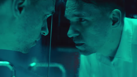 Man staring at his reflection in a disturbing light