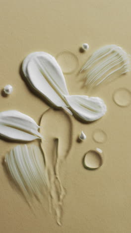 vertical video of beauty product cream smudges with copy space on yellow background