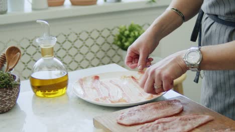 Woman-shifting-prosciutto-from-baking-paper-on-plate