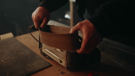 Removing-an-old,-damaged-sanding-belt-from-an-electric-belt-grinder