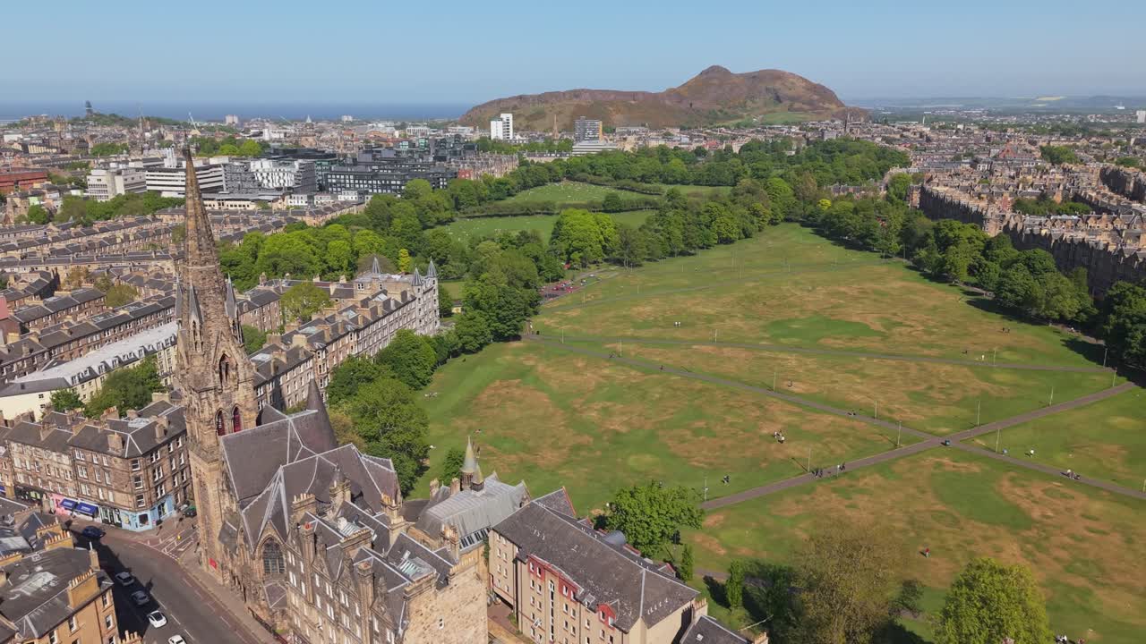 Drone footage reveals Barclay Viewforth Church in the foreground, lush meadows nearby, and the expansive Holyrood Park stretching in the background