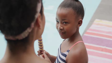 Happy-african-american-mother-and-daughter-eating-ice-cream-by-swimming-pool,-slow-motion