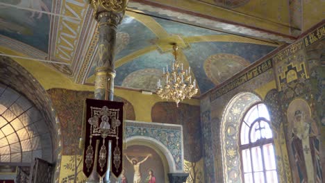 ukraine, kyiv, pechersk lavra, interior of the famous church,a young priest and some people, primarily women, praying in front of "crucified jesus"s fresco, day time ceremony in the cosy church.