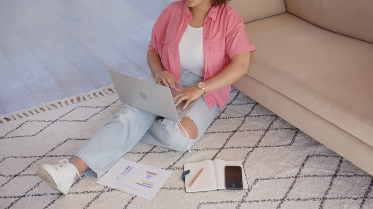 Sitting on floor, woman in casual clothes reaching for tablet in living room