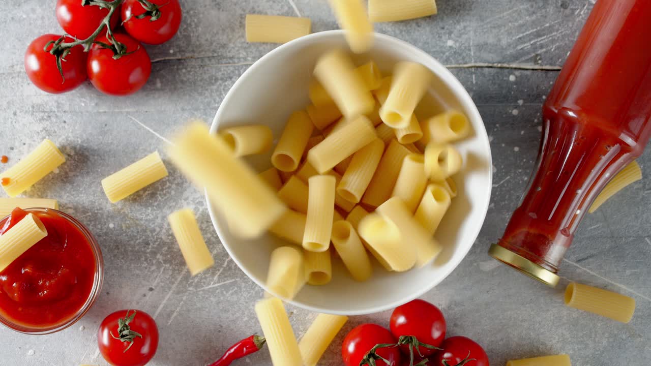 la pasta seca de cannelloni cayendo en un cuenco en la mesa.