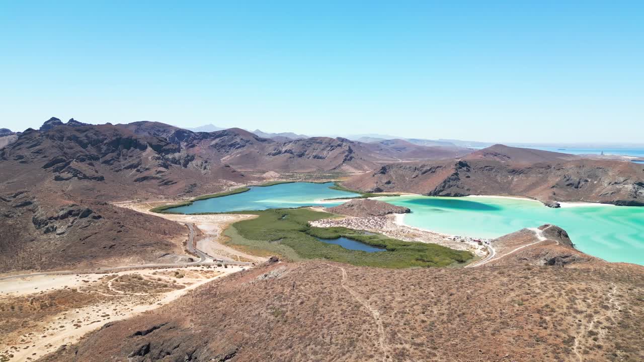 Calm desert landscape with turquoise lagoon and distant mountains in La Paz, Mexico