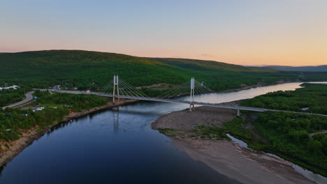 Aerial-view-orbiting-the-Sami-Bridge-and-river,-sunset-in-Utsjoki,-Finland