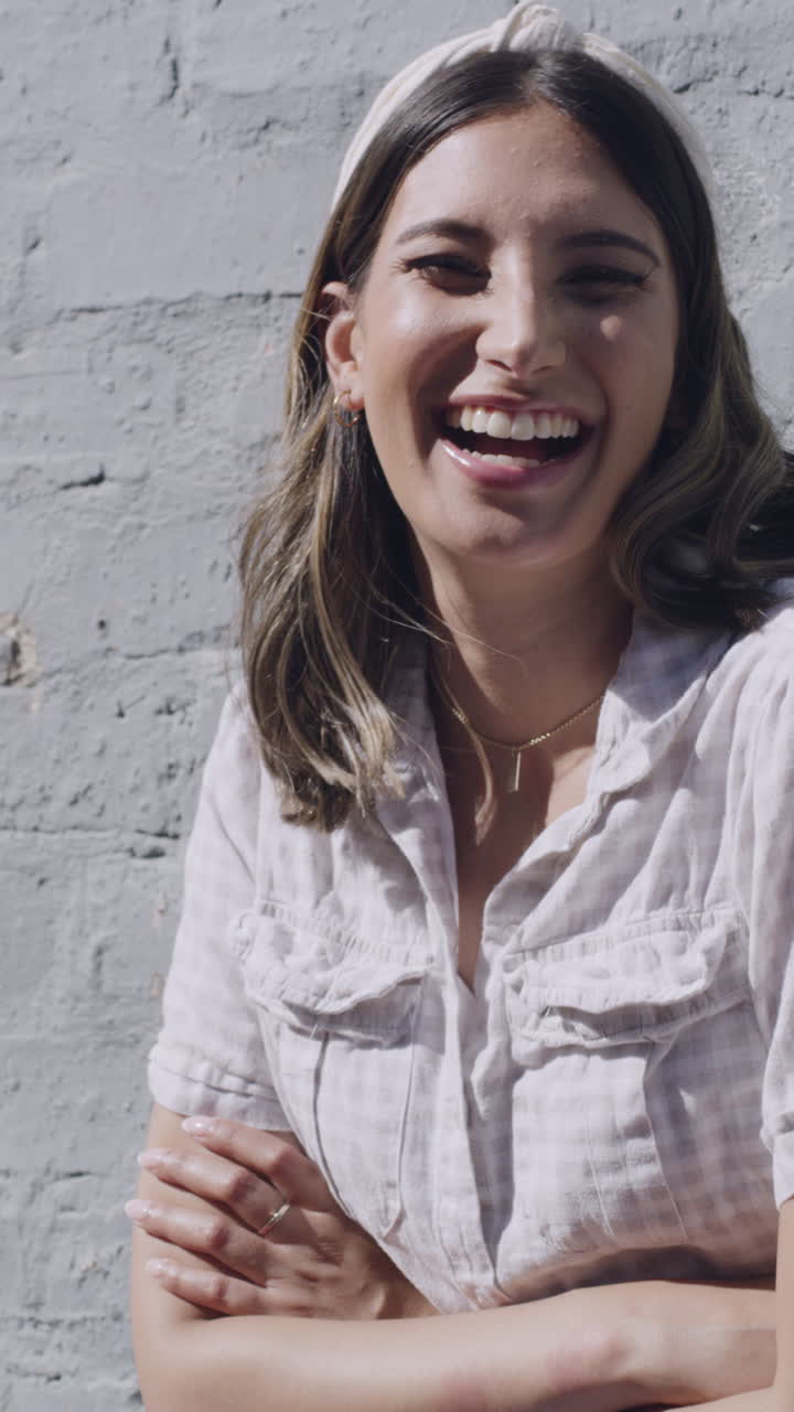 Mujer joven riendo y sonriendo frente a una pared de ladrillo