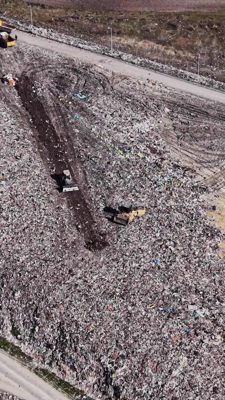 Bulldozers leveling waste on a landfill slope