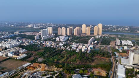 aerial of distinct skyline emerges, dominated by numerous tall, light-coloured residential high-rise towers clustered together. beyond these high-rises, a hazy horizon stretches into the distance