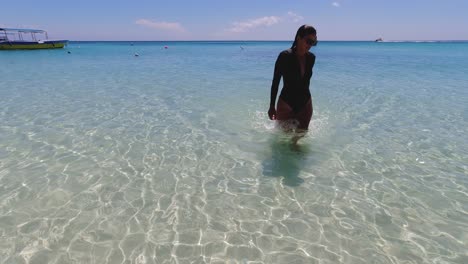 una joven latina emerge lentamente del cálido agua tropical del mar.