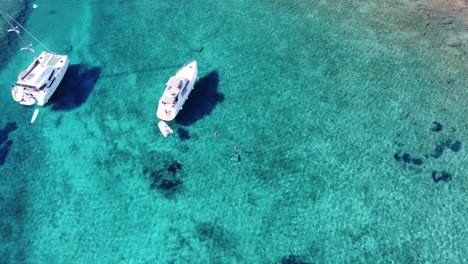 Woman-swimming-beside-Catamaran-Yacht-anchored-in-Turquoise-transparent-water-of-Blue-Lagoon-on-Veliki-Budikovac-Island,-Croatia