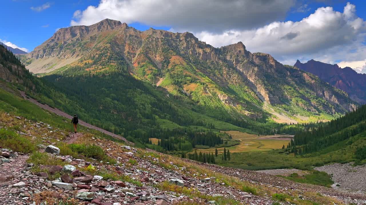 Hiking trail Maroon Bells Wilderness Maroon Crater Lake green summer valley Colorado sunny clouds movement Aspen Snowmass rugged terrain Elk Range Rocky Mountains White River Forest blue sky static