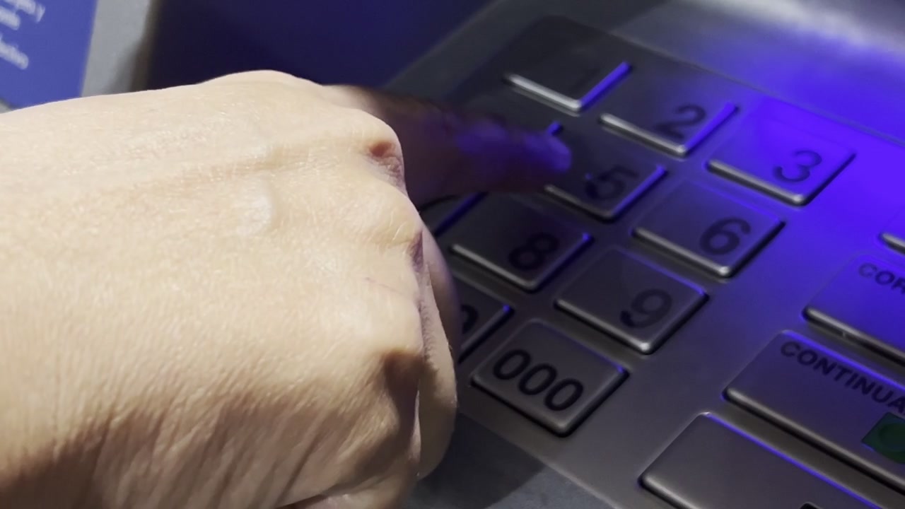 Una mano digita il codice PIN di accesso al bancomat, commette un errore e lo corregge