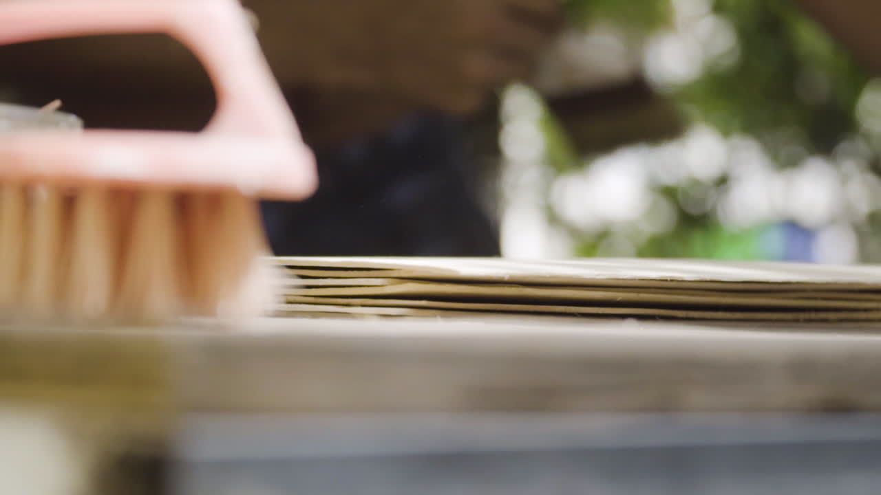 Topless man out of focus brushing off dust with brush in woodwork workshop