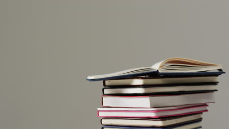 primer plano de un libro abierto en una pila de libros sobre un fondo gris, en cámara lenta