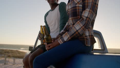 pareja con botellas de cerveza sentada en una camioneta en la playa 4k