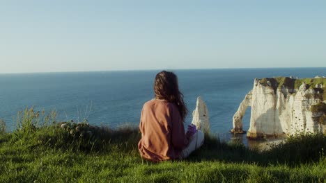 mujer relajándose en un acantilado costero, francia