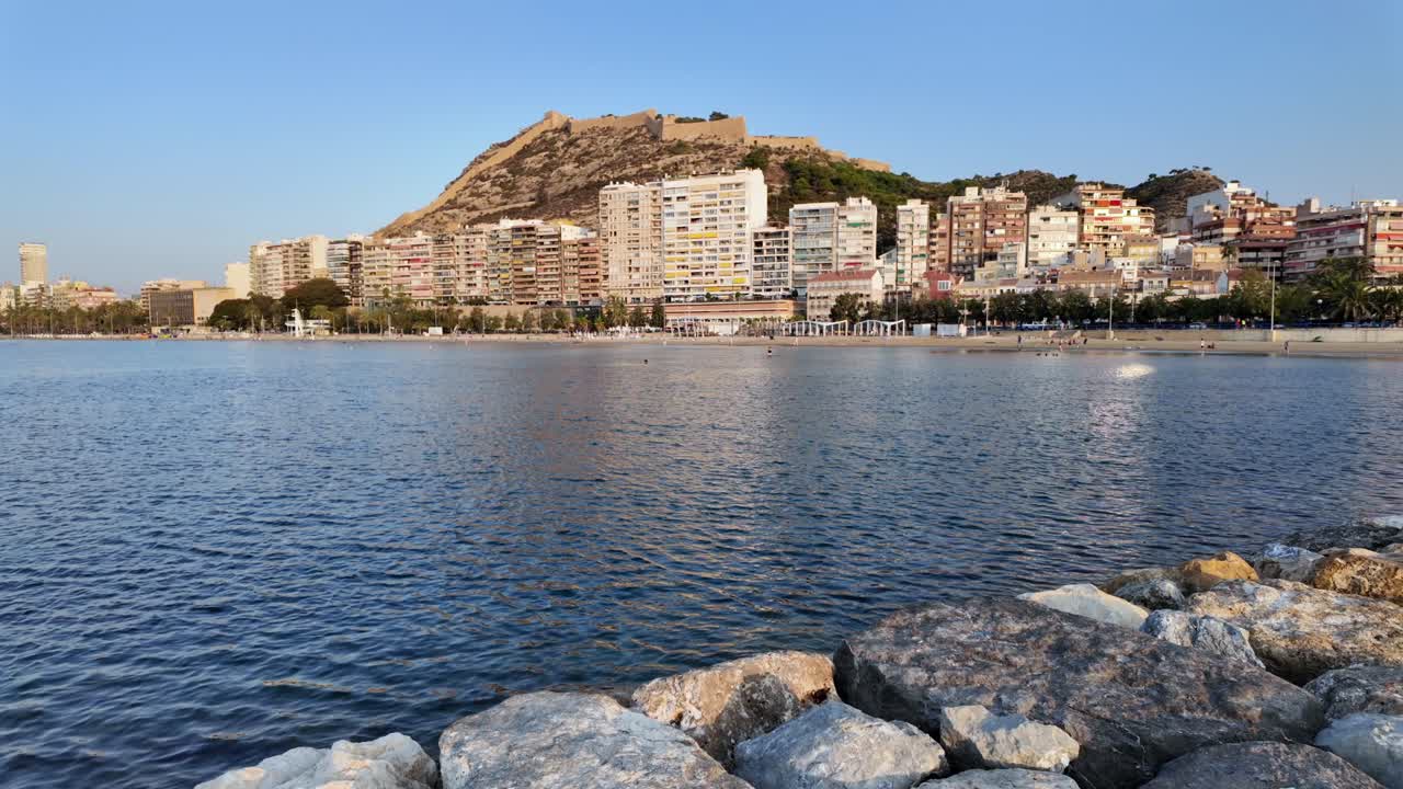 View of Alicante waterfront and Santa Bárbara Castle in golden evening light