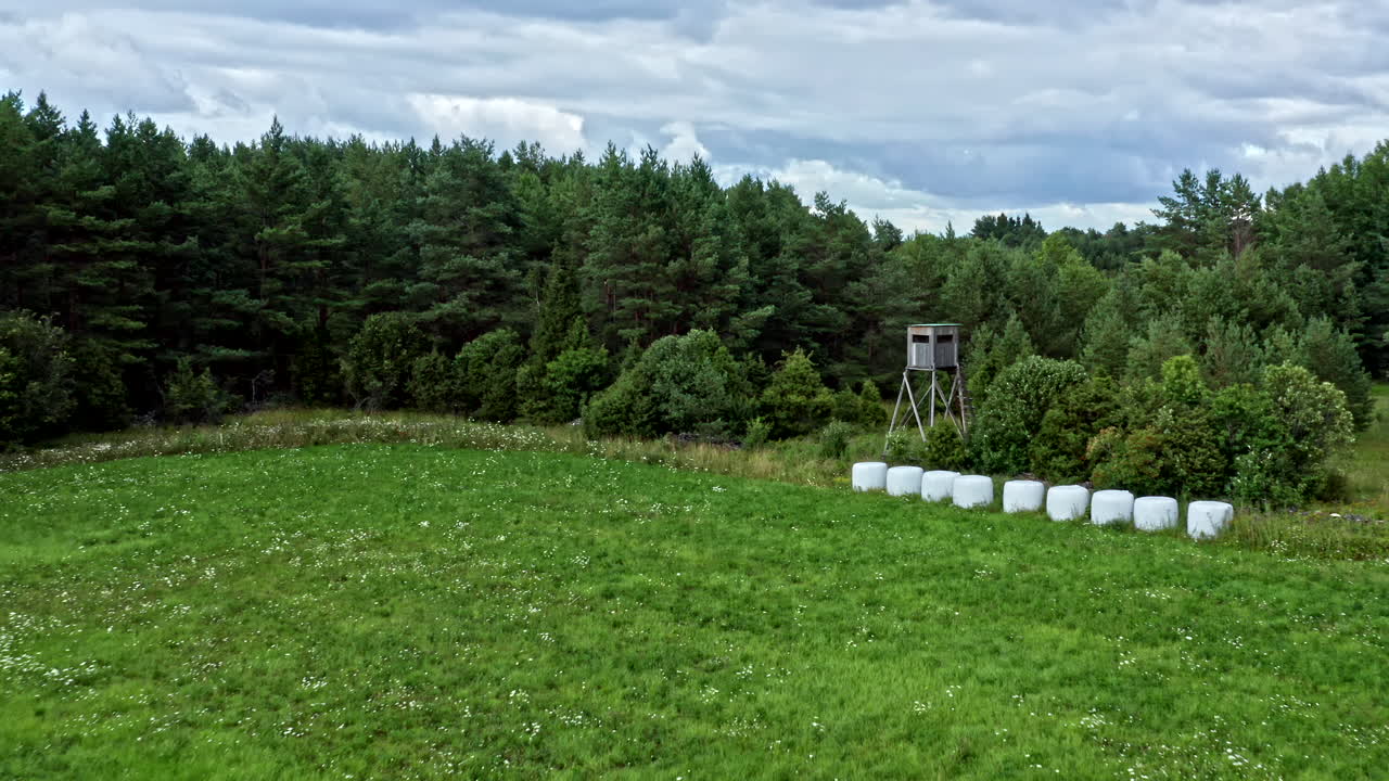Aerial View of Raised Blind Shooting Tower on Field With Forest in the Background - Backwards Dolly Shot