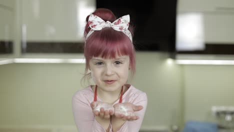 una niña cubierta de harina horneando en la cocina