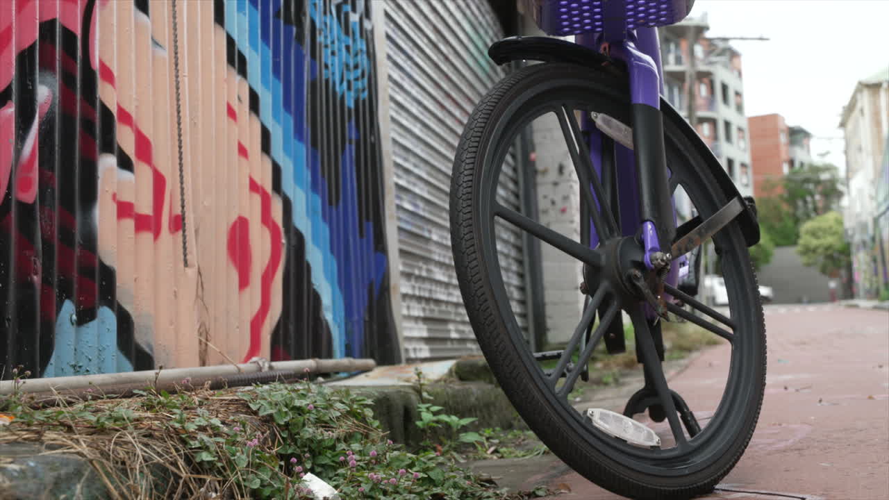 A hire bike stands next to a graffiti'd wall on a quiet urban residential street, innerwest Sydney Australia