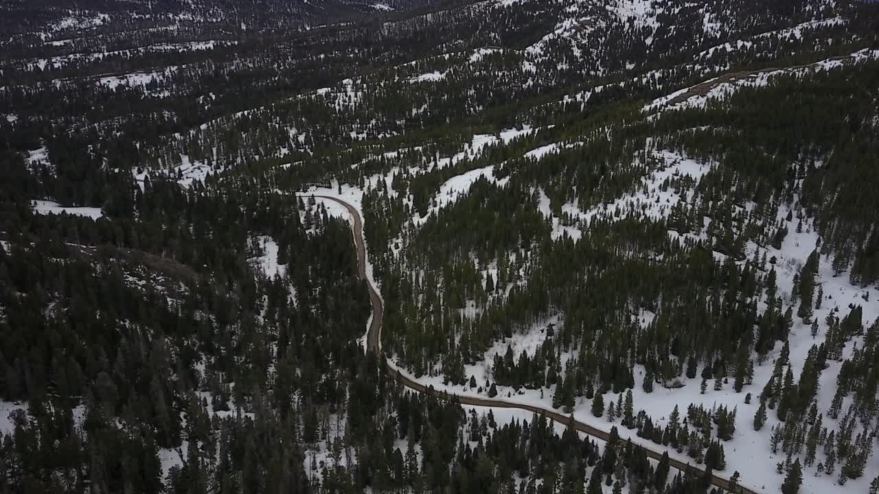 Aerial View of a Mountain Dirt Road in Winter. Snow and Pine Trees in Montana. Dynamic Tilting Shot.
