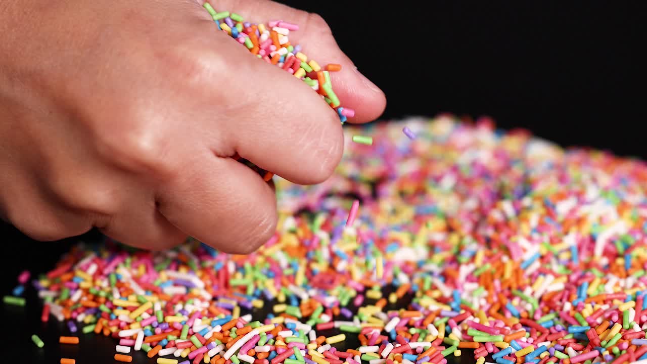 Mani con zuccherini colorati su una superficie
