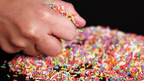 hands interacting with colorful sprinkles on surface