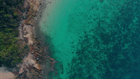 red-buoy-floats-against-narrow-sand-and-rock-empty-coastline