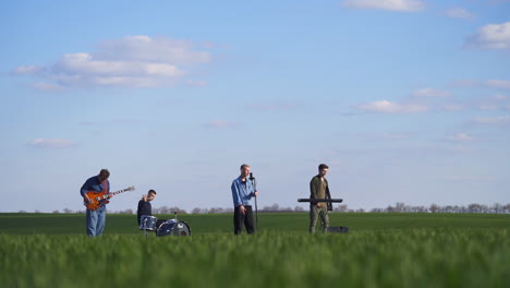 four musicians performing their energetic music in the plantations. young men create music, sing and move actively. nature backdrop.