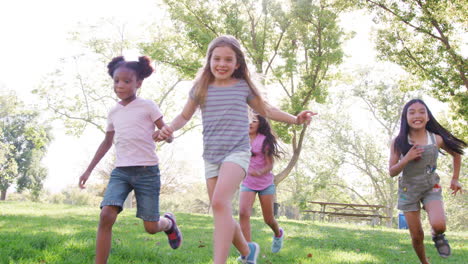 group of young girls with friends playing football in park shot in slow motion