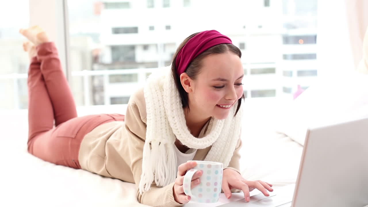 그녀의 침대에 노트북을 사용하는 예쁜 갈색