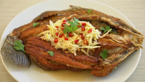 fried sea bass fish with fish sauce and spicy salad on plate