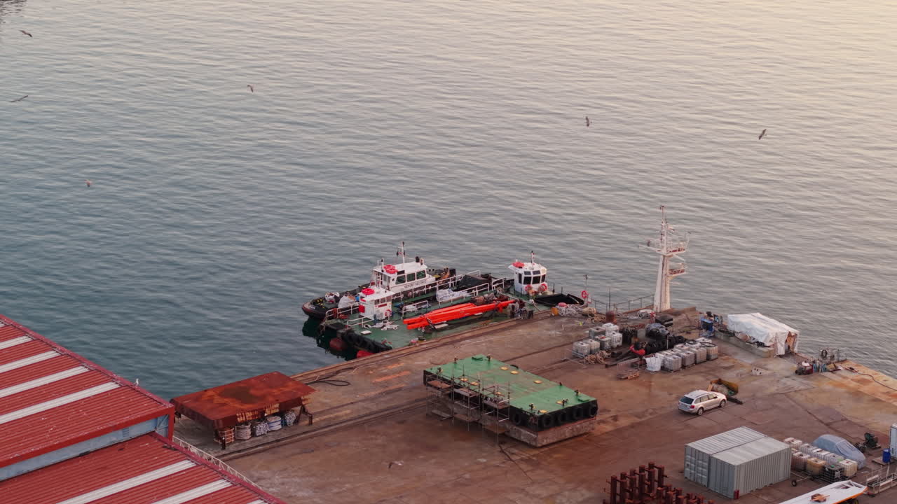 Aerial shot of Genoa port with docked boats, calm sea, warehouses and containers