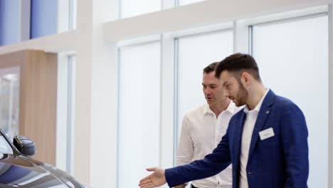 a salesman showing the new car model to a client