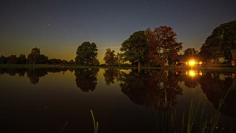 Puesta-De-Sol-Sobre-Un-Lago-Espejo-Con-Una-Casa-De-Campo-En-La-Orilla