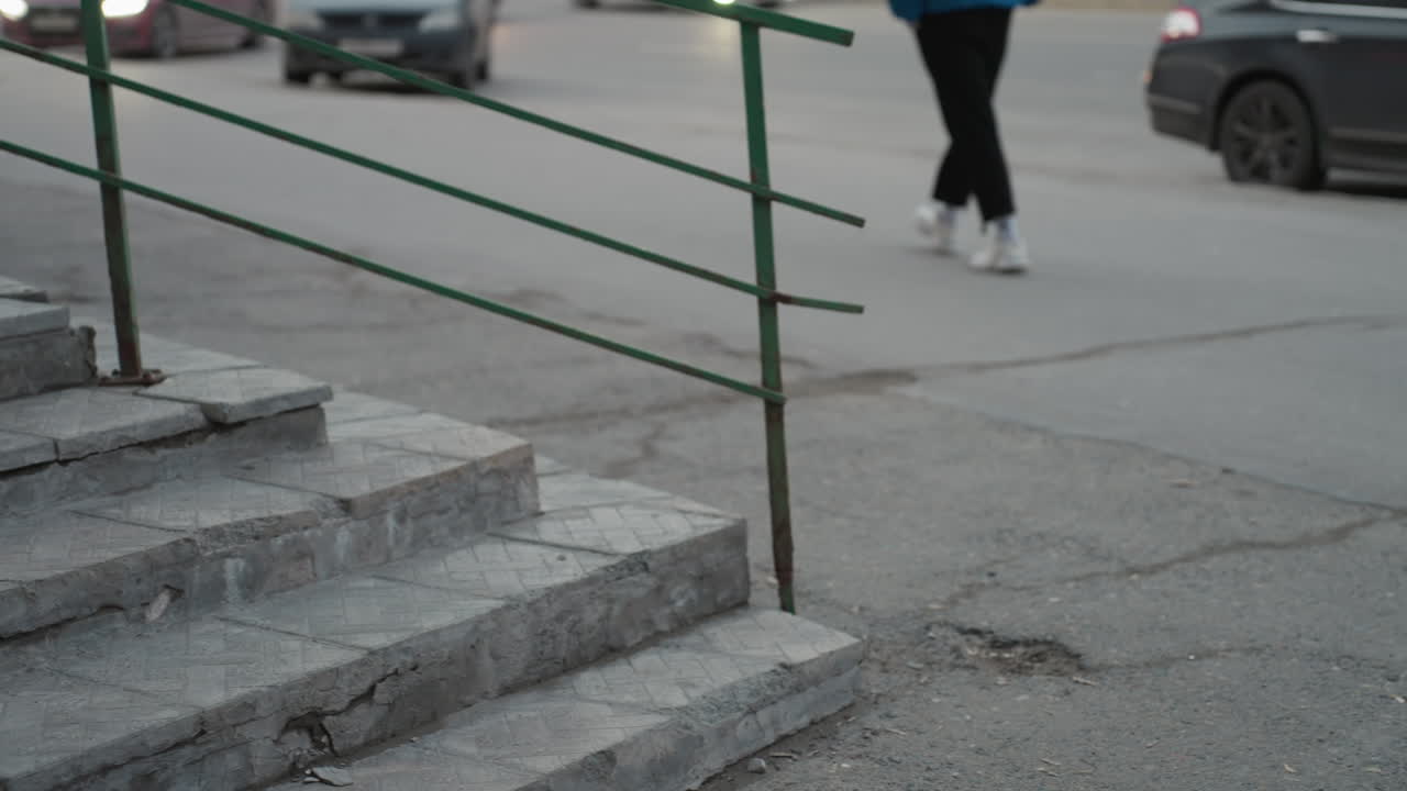 차가 지나가는 도로를 가로지르는 검은색 바지를 입은 흐릿한 인물이 있는 도시 거리의 가까운 보케 시각