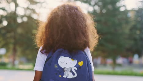 girl walking to school with a cat backpack