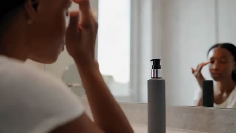 woman applying skincare in bathroom