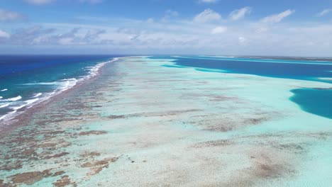 un vibrante arrecife de coral junto a aguas azules bajo un cielo despejado, toma de movimiento hacia adelante, vista aérea