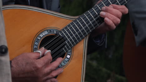 strumming a portuguese guitar outdoors. close up