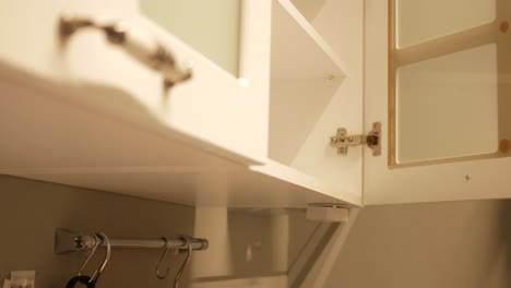 close up of a woman opening a kitchen cabinet door