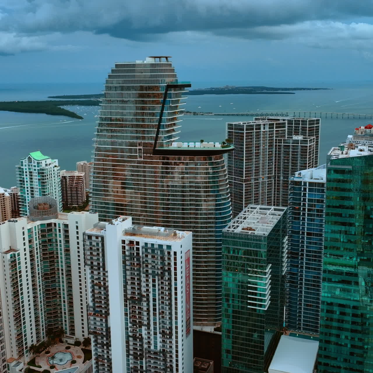 Rising above the skyscrapers on the waterfront of Miami. Opening view on Atlantic Ocean on cloudy day.