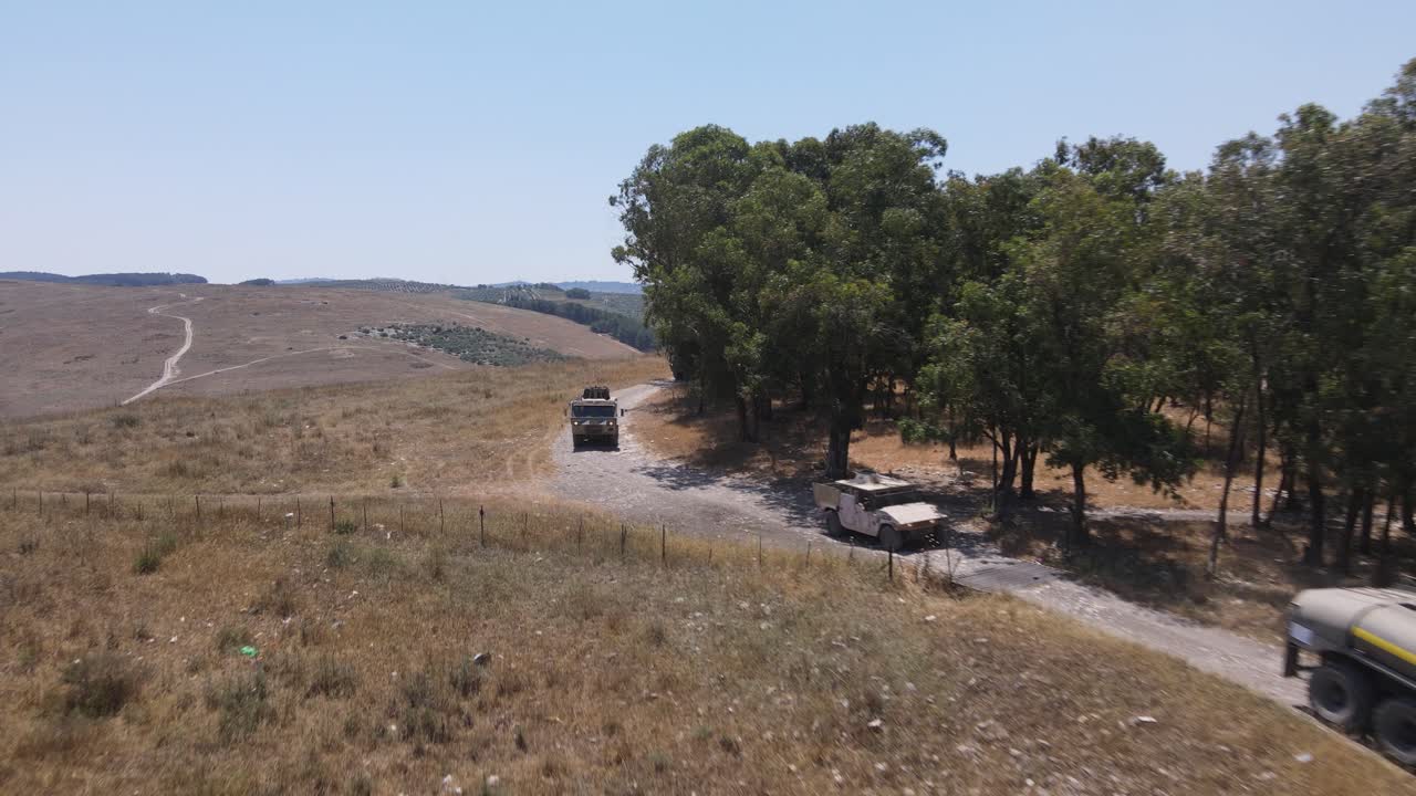 훈련장 시골길을 통해 운전하는 트럭에 탄 이스라엘 육군 분대 병사들, 공중 사격