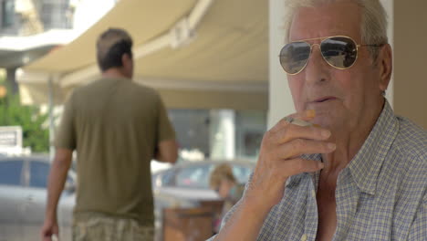 Un-Hombre-Mayor-Con-Gafas-De-Sol-Fumando-En-La-Calle